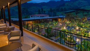 A balcony with seating and a view of a landscaped garden and mountains. - Termales del Otoño (Villamaria)