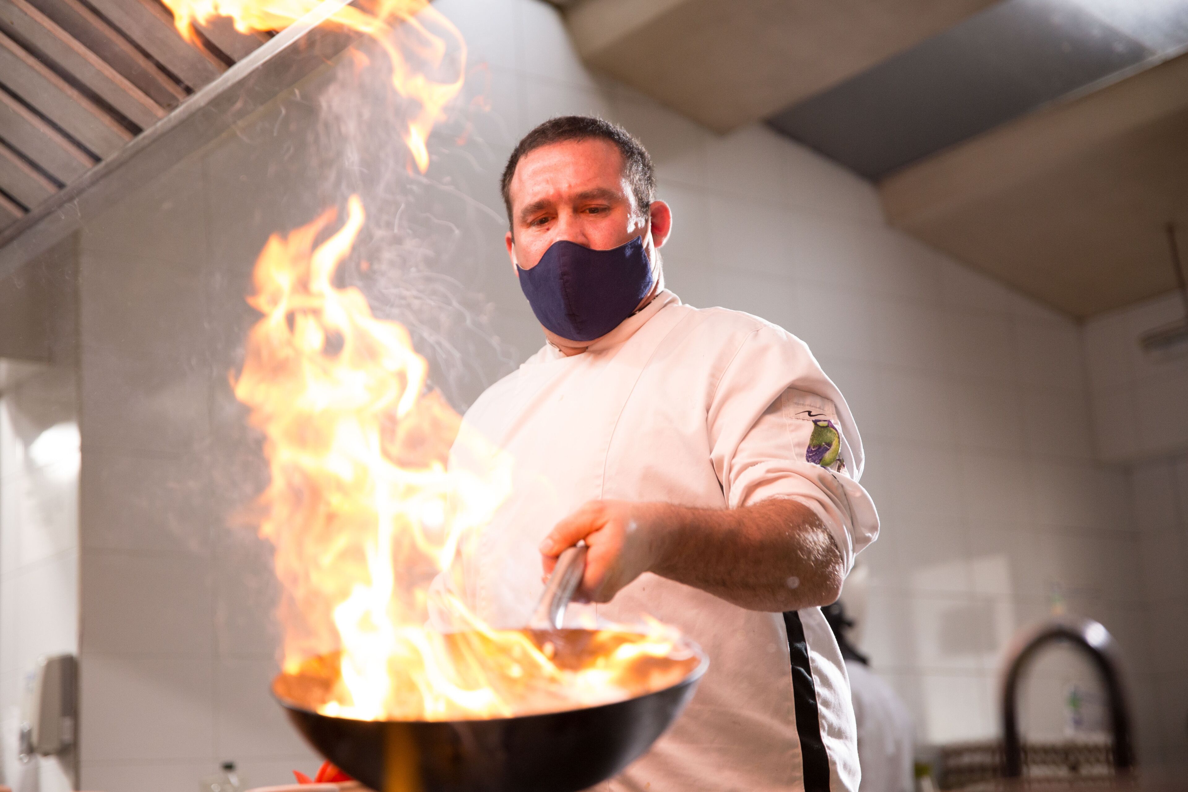 Uno chef cucina tra le fiamme in una cucina.