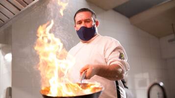 Uno chef cucina tra le fiamme in una cucina.