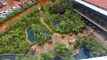 Vista aérea de un patio de hotel con piscina, abundante vegetación y zonas de estar al aire libre.