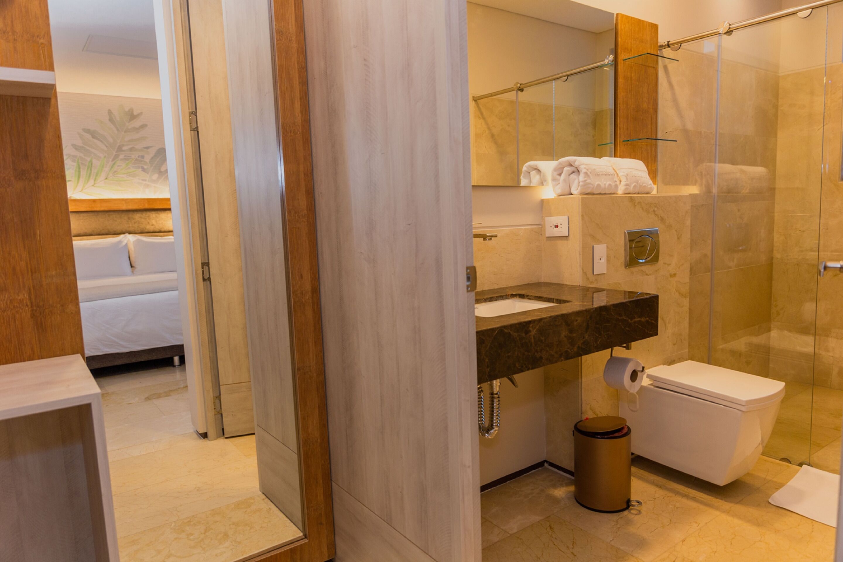 A modern bathroom with a glass shower enclosure, a marble sink, and a toilet.