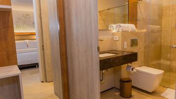 A modern bathroom with a glass shower enclosure, a marble sink, and a toilet.