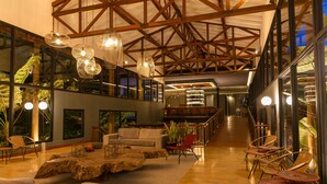A spacious lobby with a high ceiling, wooden beams, large windows, and a variety of seating options including sofas and chairs. - Termales del Otoño (Villamaria)