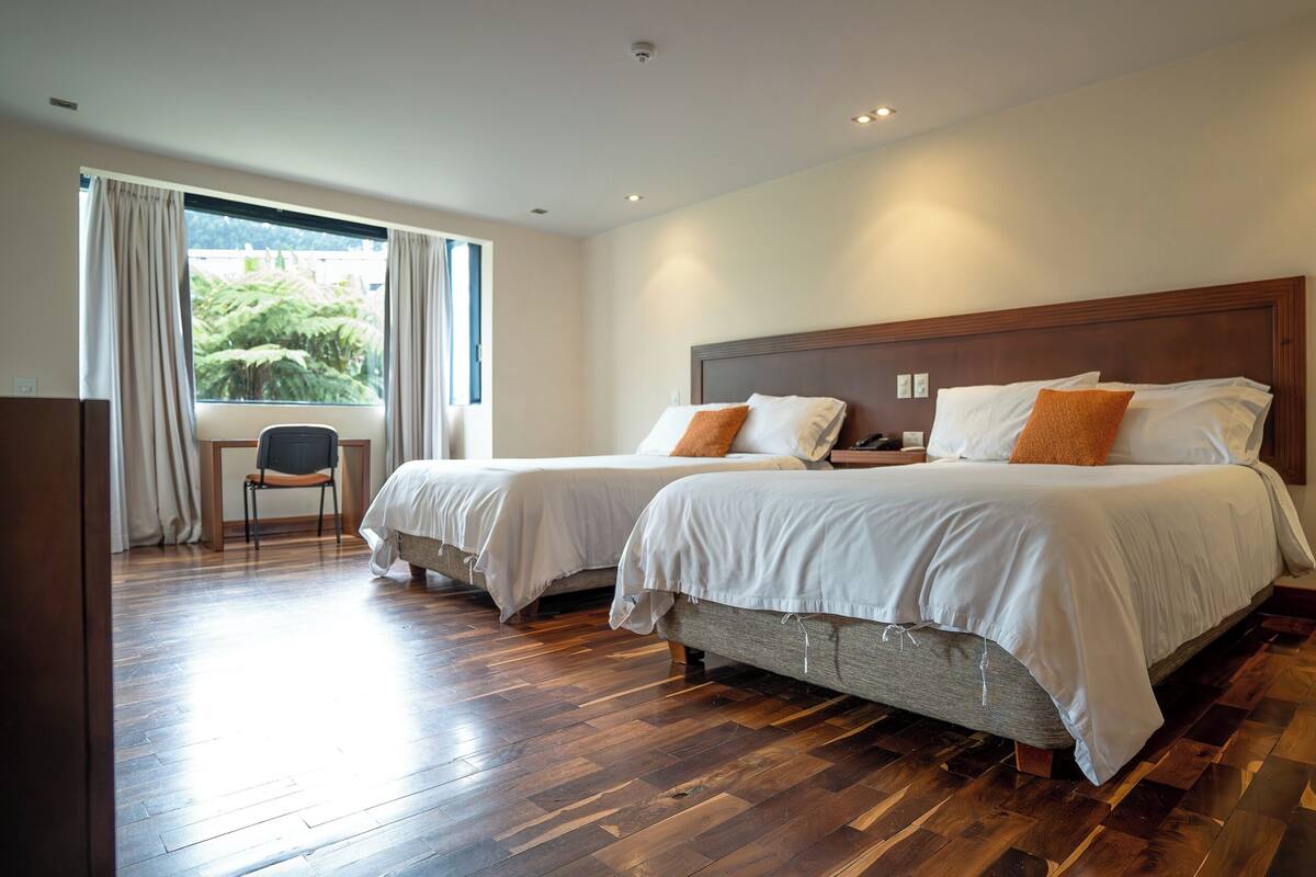 Ein Hotelzimmer mit zwei Betten, einem Schreibtisch und einem Stuhl.