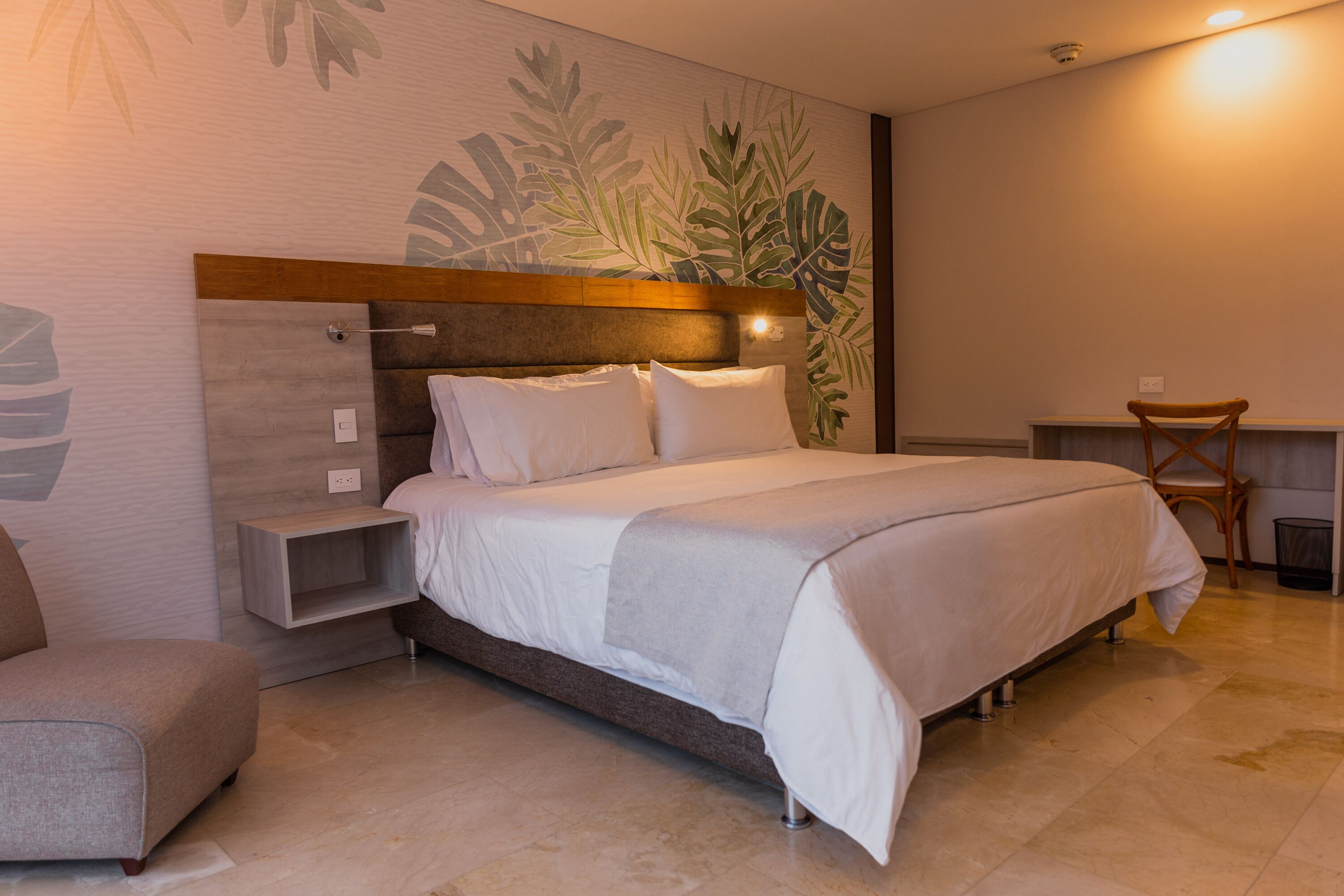 A modern bedroom with a large bed, a nightstand, a chair, and a desk.