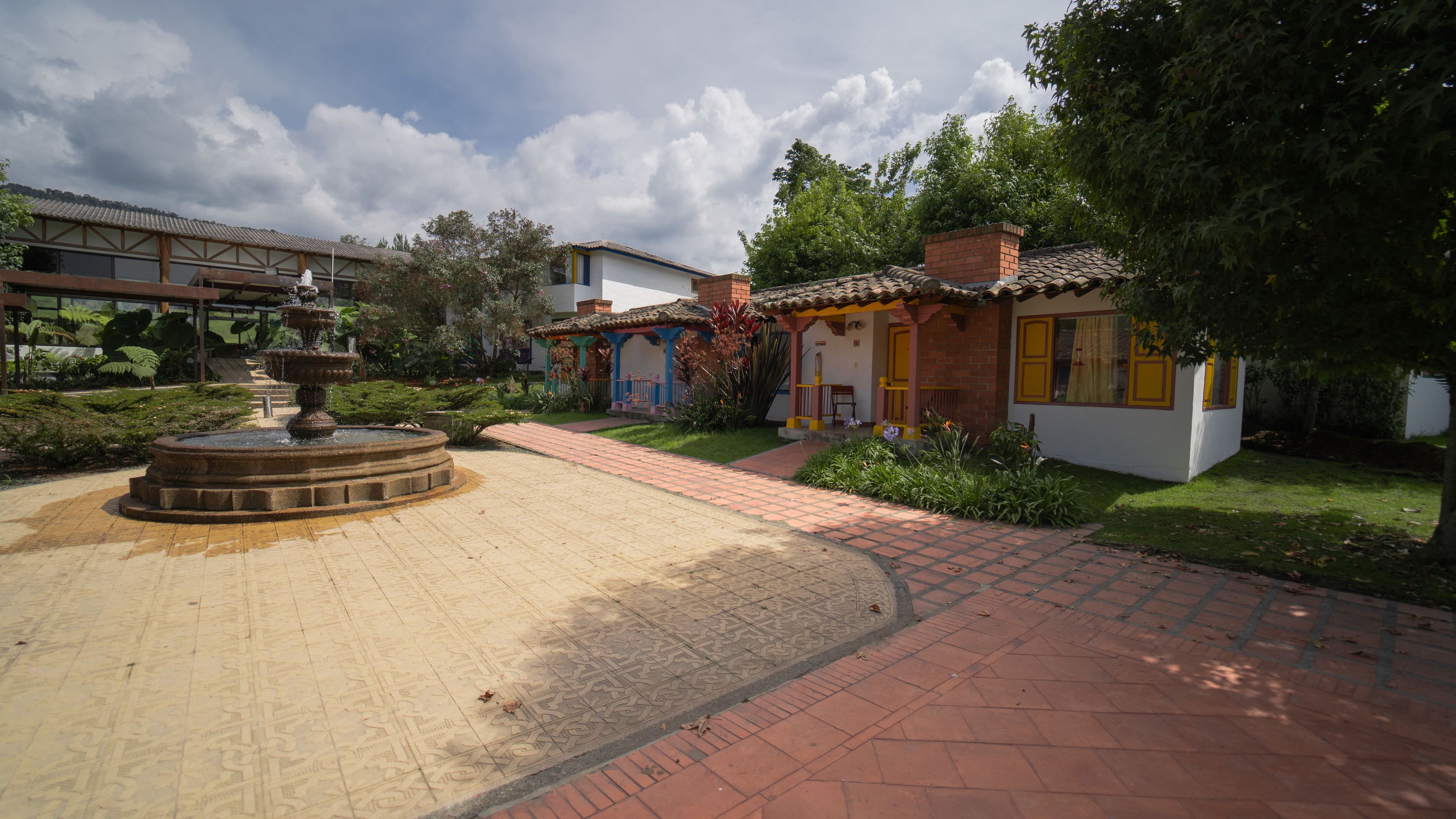 A courtyard with a fountain, paved walkways, and colorful buildings with traditional architecture.