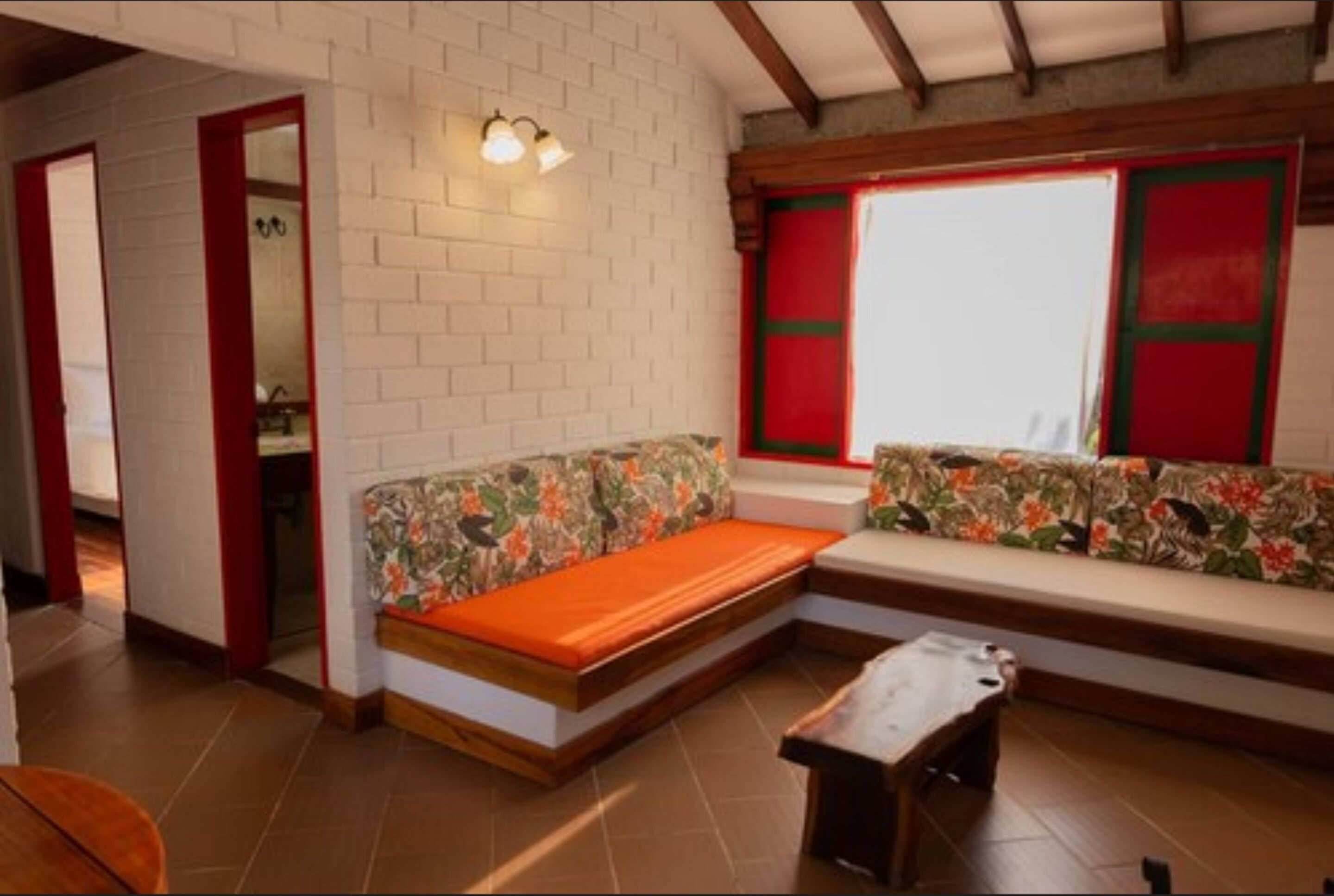 Een kamer met een zithoek tegen een witte bakstenen muur, een houten bank en een kleine tafel.