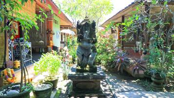 Stroll through a serene courtyard surrounded by lush greenery and traditional buildings with red-tiled roofs.