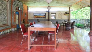 A conference room with a long table, red chairs, and a large painting on the wall. - Mertha Jati Hotel & Bungalow (Kuta)