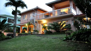 Uma casa de dois andares com uma varanda, uma escadaria e um jardim bem cuidado.
