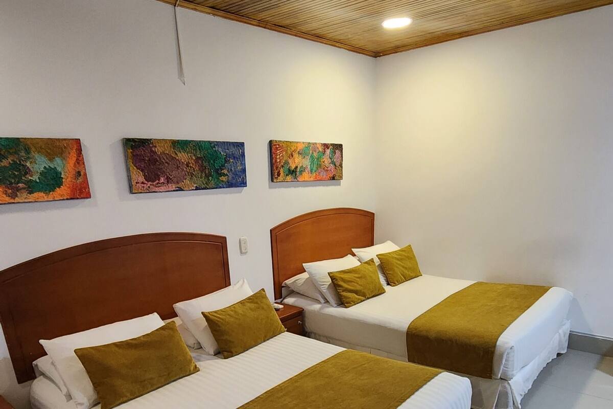 A hotel room with two beds, wooden headboards, and a ceiling with wooden slats.