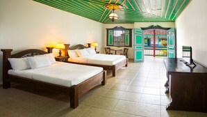 A hotel room with two beds, a desk, and a view of the outside. - Decameron Las Heliconias (Quimbaya)
