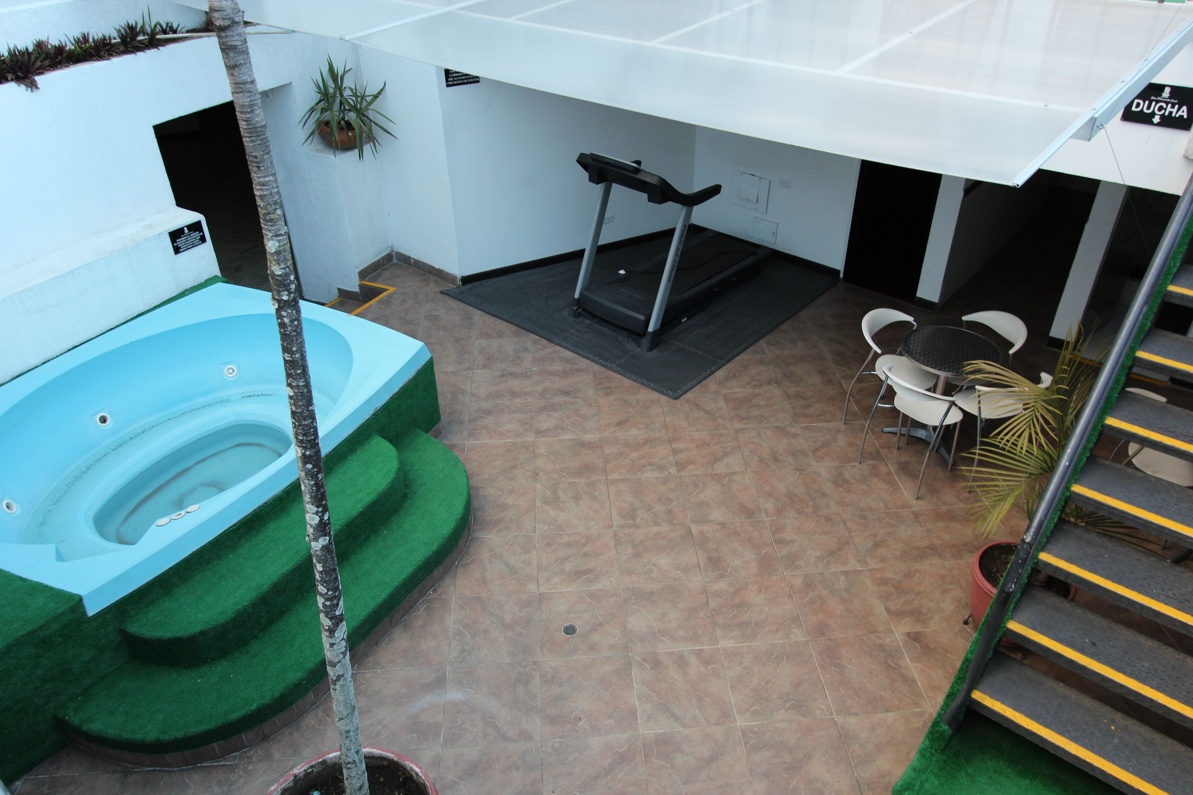 A spa area with a hot tub, a treadmill, and a seating area with chairs and a table.