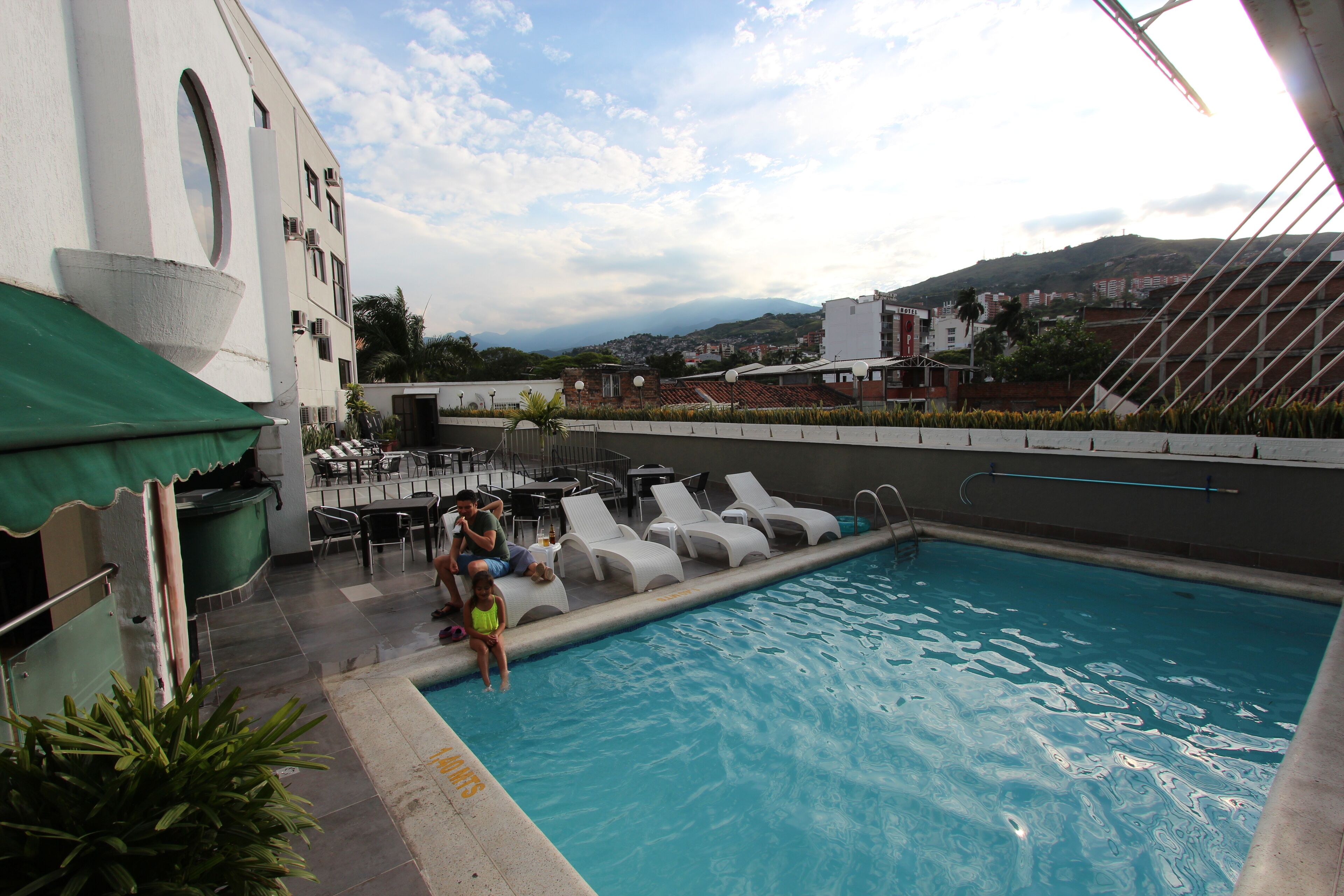 Una piscina en la azotea con sillones de descanso y zona de bar.