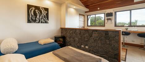 Una habitación con cama, pared de piedra, chimenea y ventana con vistas.