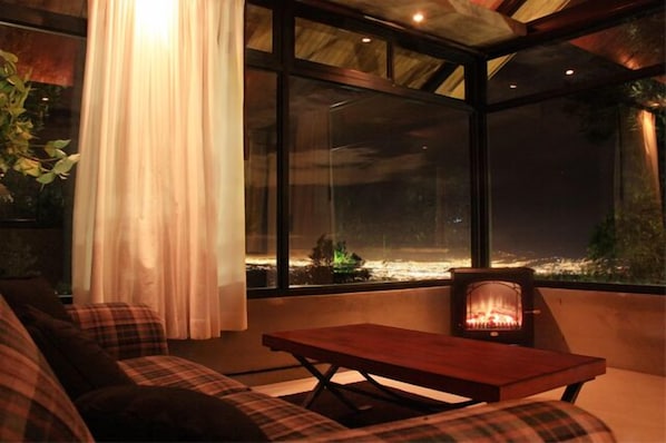 A cozy room with a large window, a fireplace, and a plaid sofa. - Altura Hotel (San Juan)