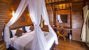 Ein Zimmer aus Holz mit einem Bett unter einem Baldachin, einer Holzbank, einem Spiegel und einem Nachttisch.