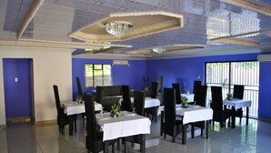 A dining area with tables set for six, blue walls, and a chandelier. - Lapologa Bed and Breakfast (Tzaneen)