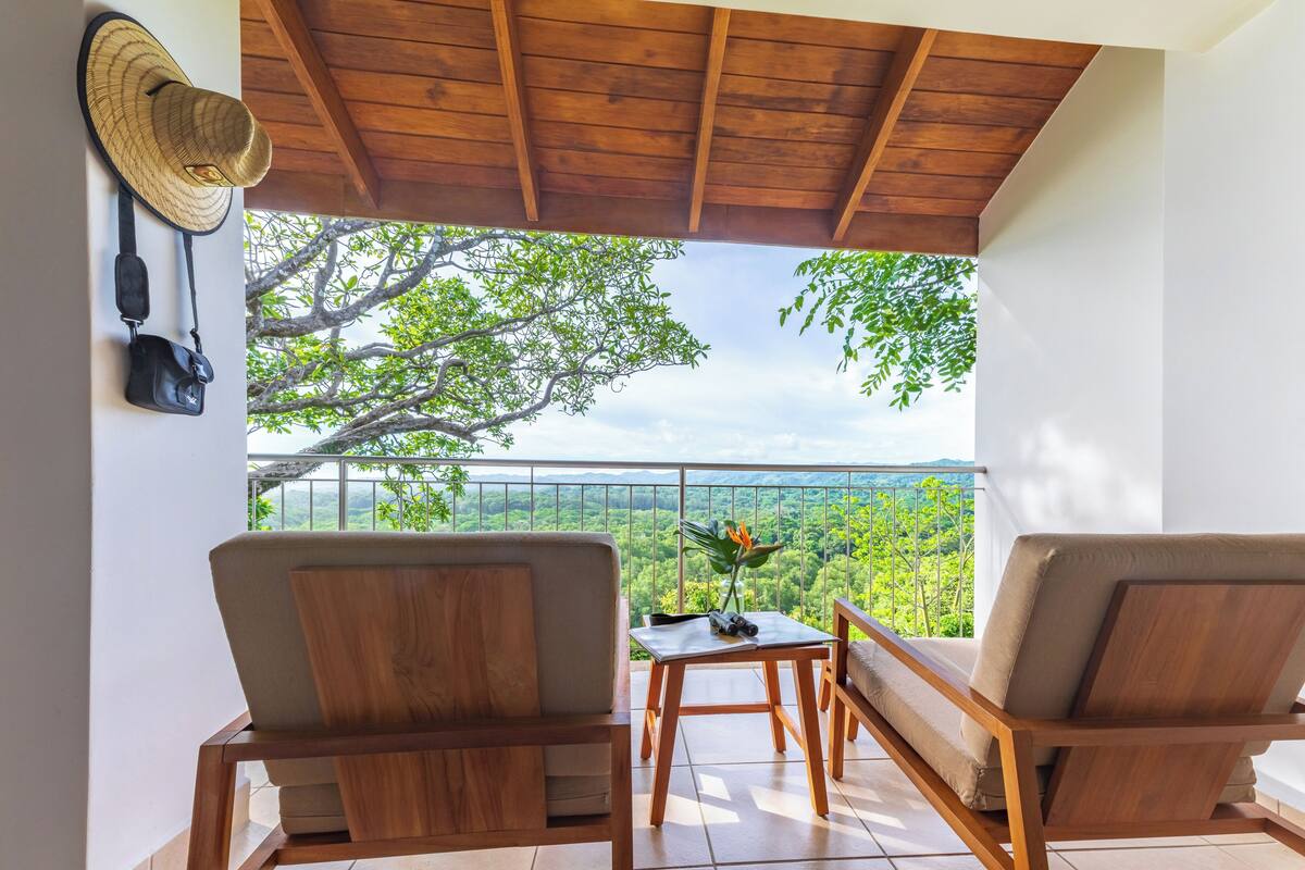 Un balcon doté de mobilier en bois et offrant une vue sur un paysage luxuriant.
