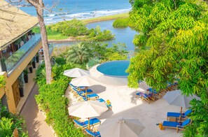 Un resort con piscina, sillas de descanso y vistas al océano.