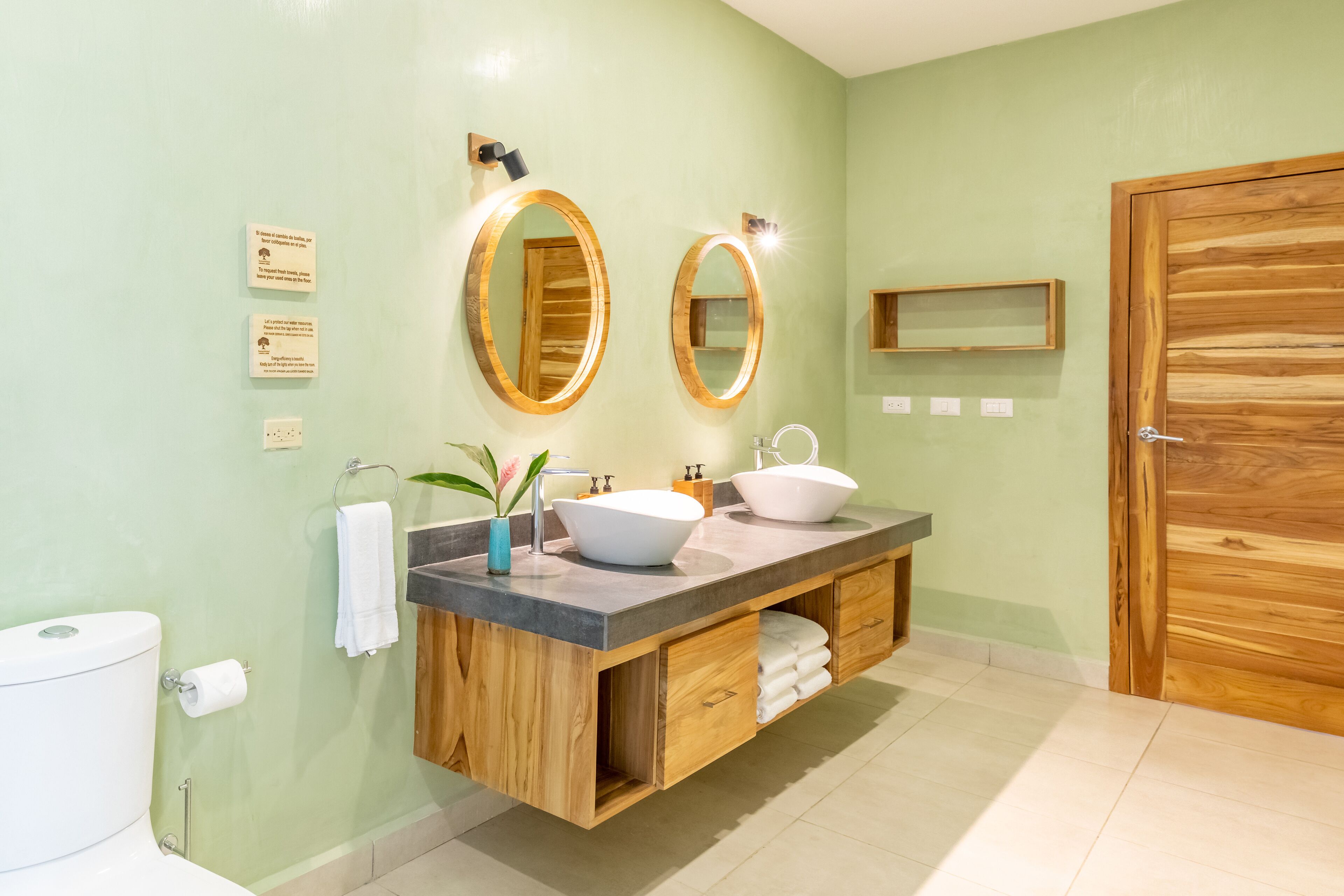 Une salle de bain avec un meuble-lavabo en bois, deux vasques et un grand miroir.