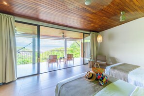 Habitación de hotel con dos camas, un balcón con vistas y un área de comedor con sillas y una mesa.