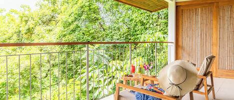A balcony with a wooden chair, a table with a hat, and a pair of slippers.