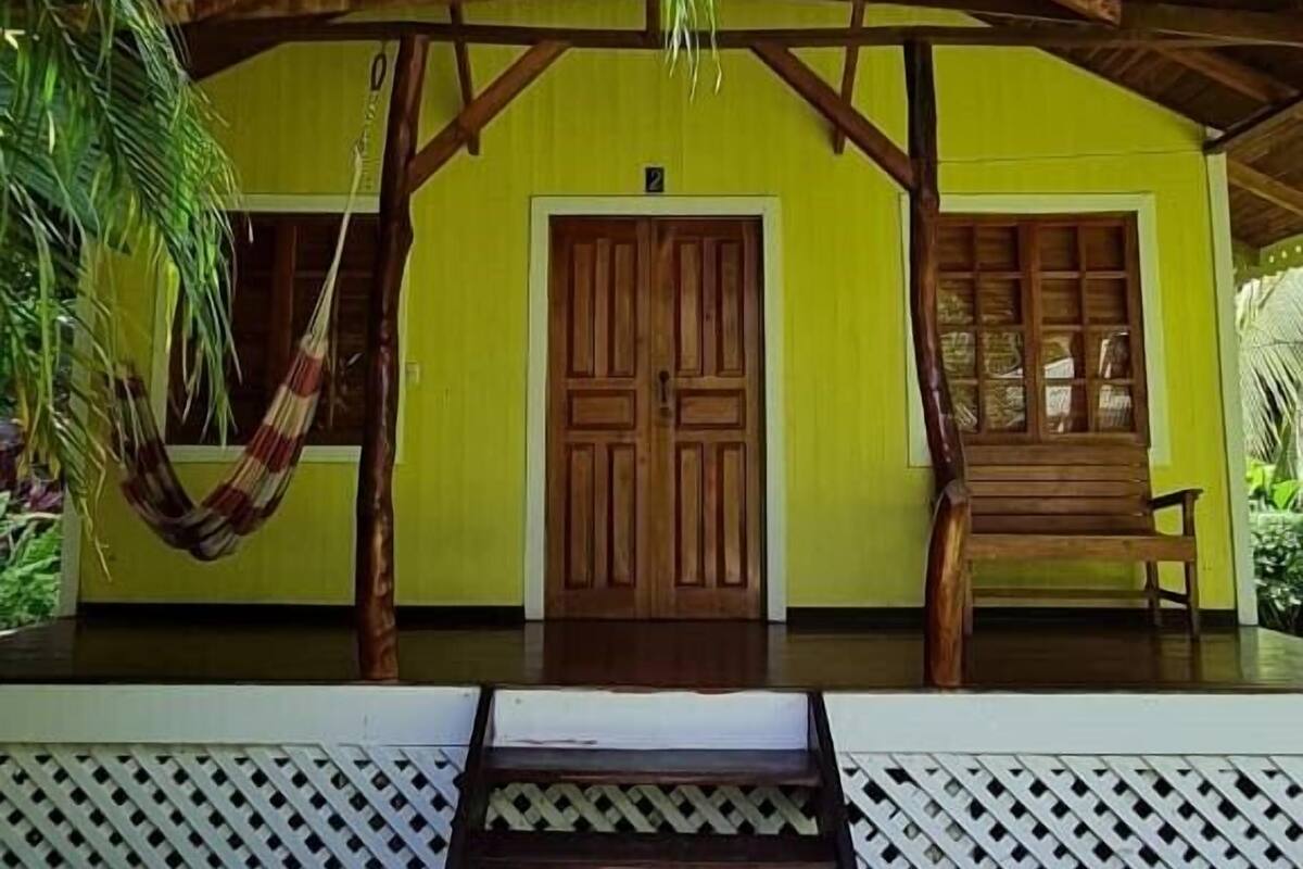 A yellow building with a wooden door and a porch.