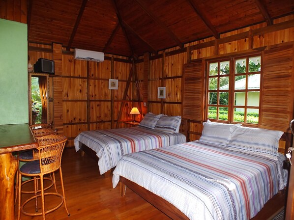 A wooden cabin room with two beds, a desk, and a chair. - Ciudad Pérdida Ecolodge (Cahuita)