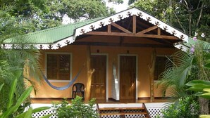 A small, single-story house with a porch, surrounded by lush greenery. - Ciudad Pérdida Ecolodge (Cahuita)