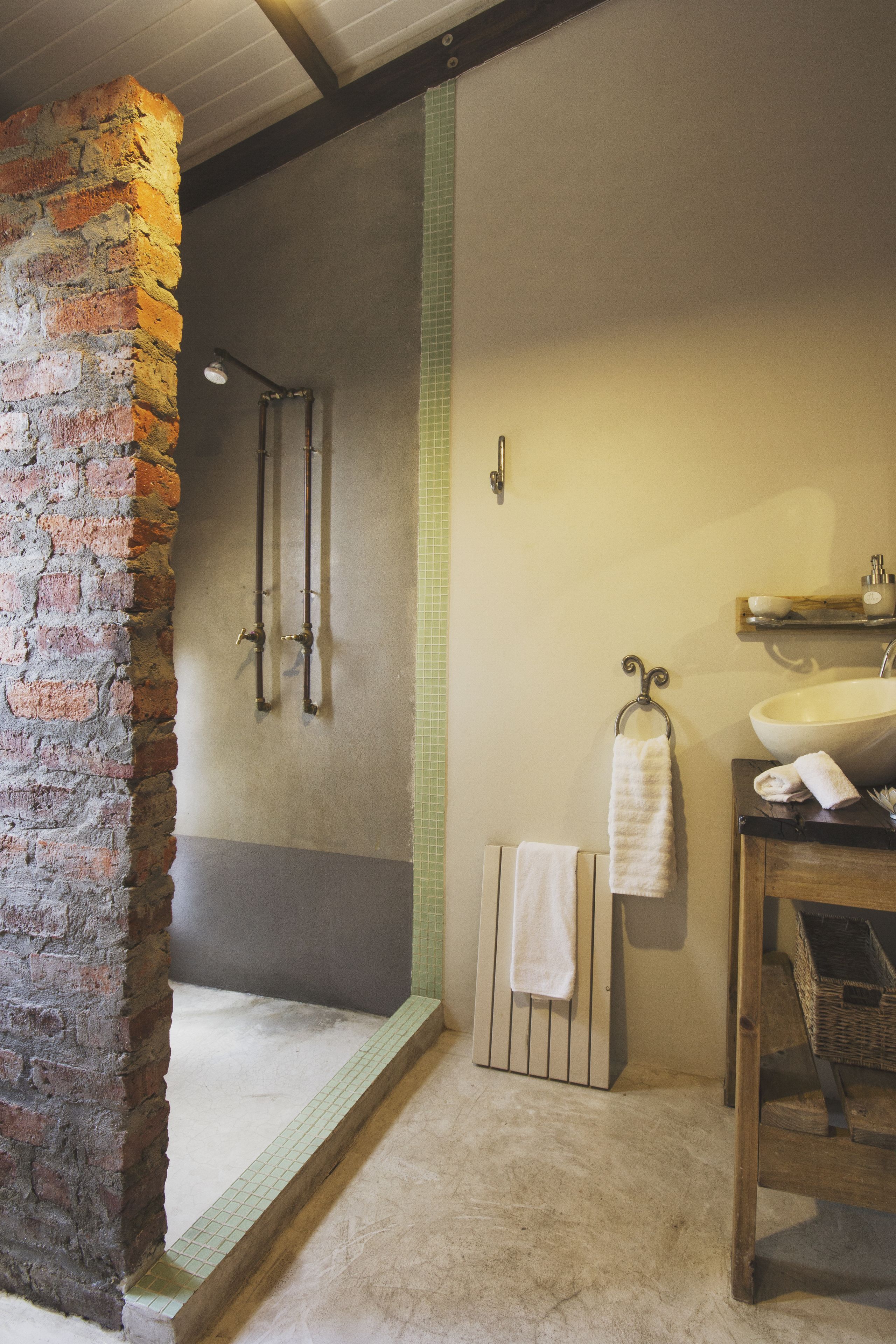 Une salle de bain avec un mur en briques, une baignoire, un lavabo et un porte-serviettes.