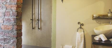 Une salle de bain avec un mur en briques, une baignoire, un lavabo et un porte-serviettes.