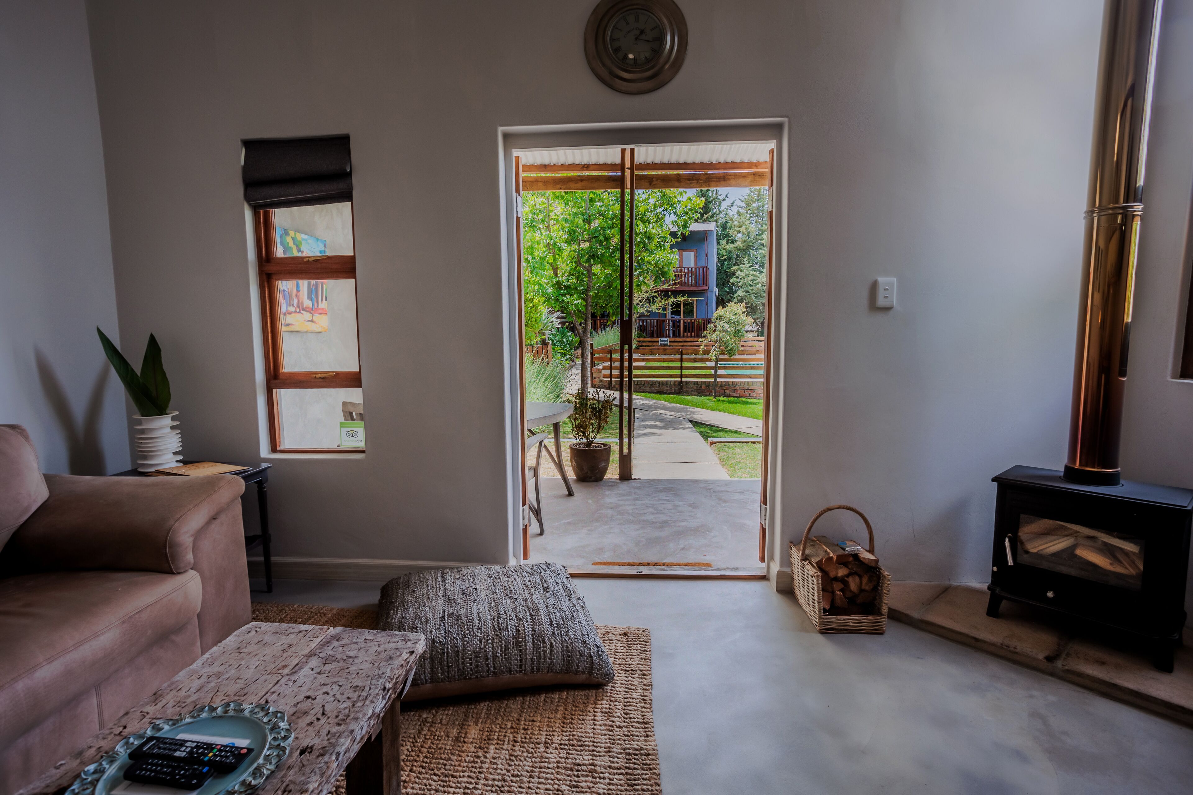 A living room with a sofa, a coffee table, a fireplace, and a view of a garden through a glass door.