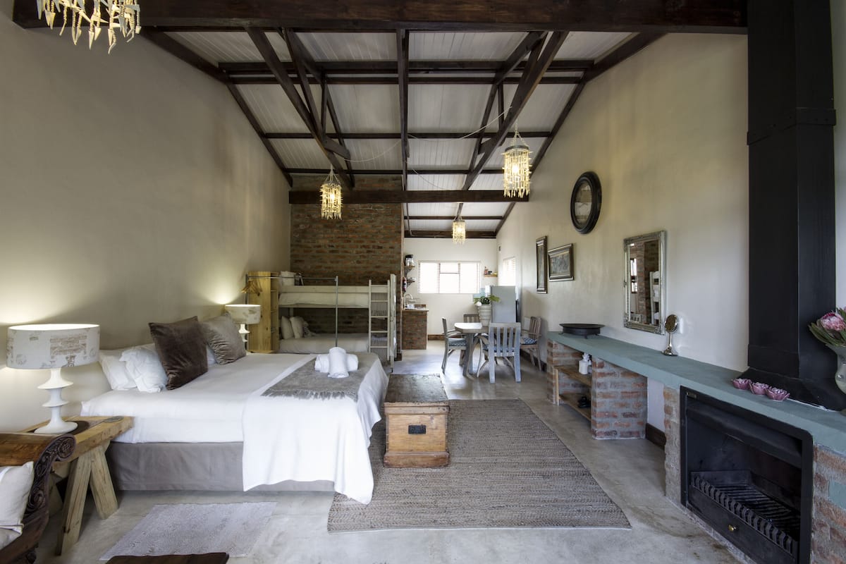 Een gezellige slaapkamer met een bed, nachtkastjes, een dressoir, een open haard en een zithoek met stoelen en een tafel.