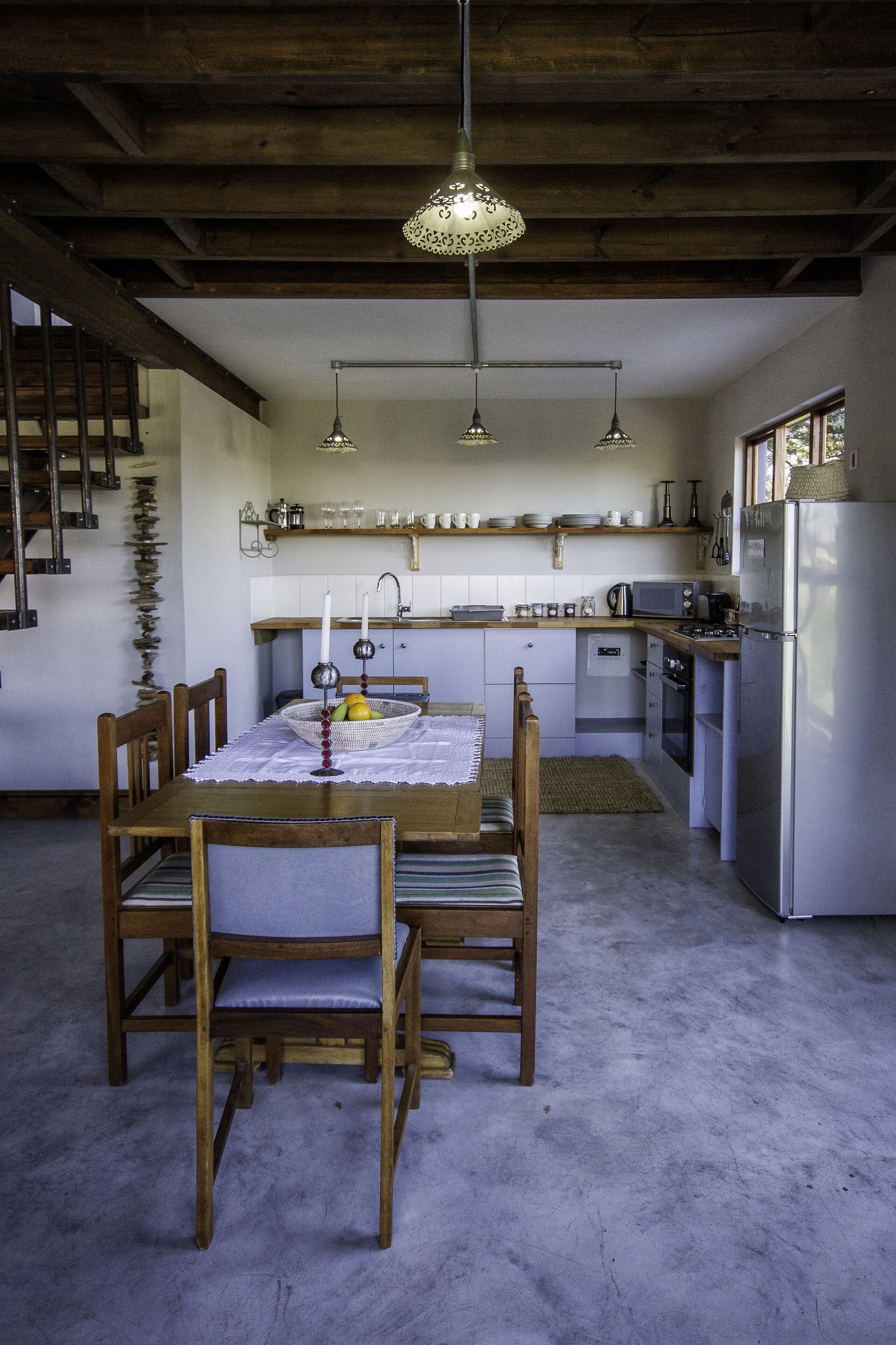A kitchen with a dining table, chairs, a refrigerator, and a microwave.