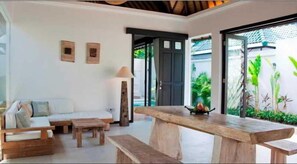A modern interior with a wooden bench, a sofa, and a lamp. - Artemis Villa (Seminyak)