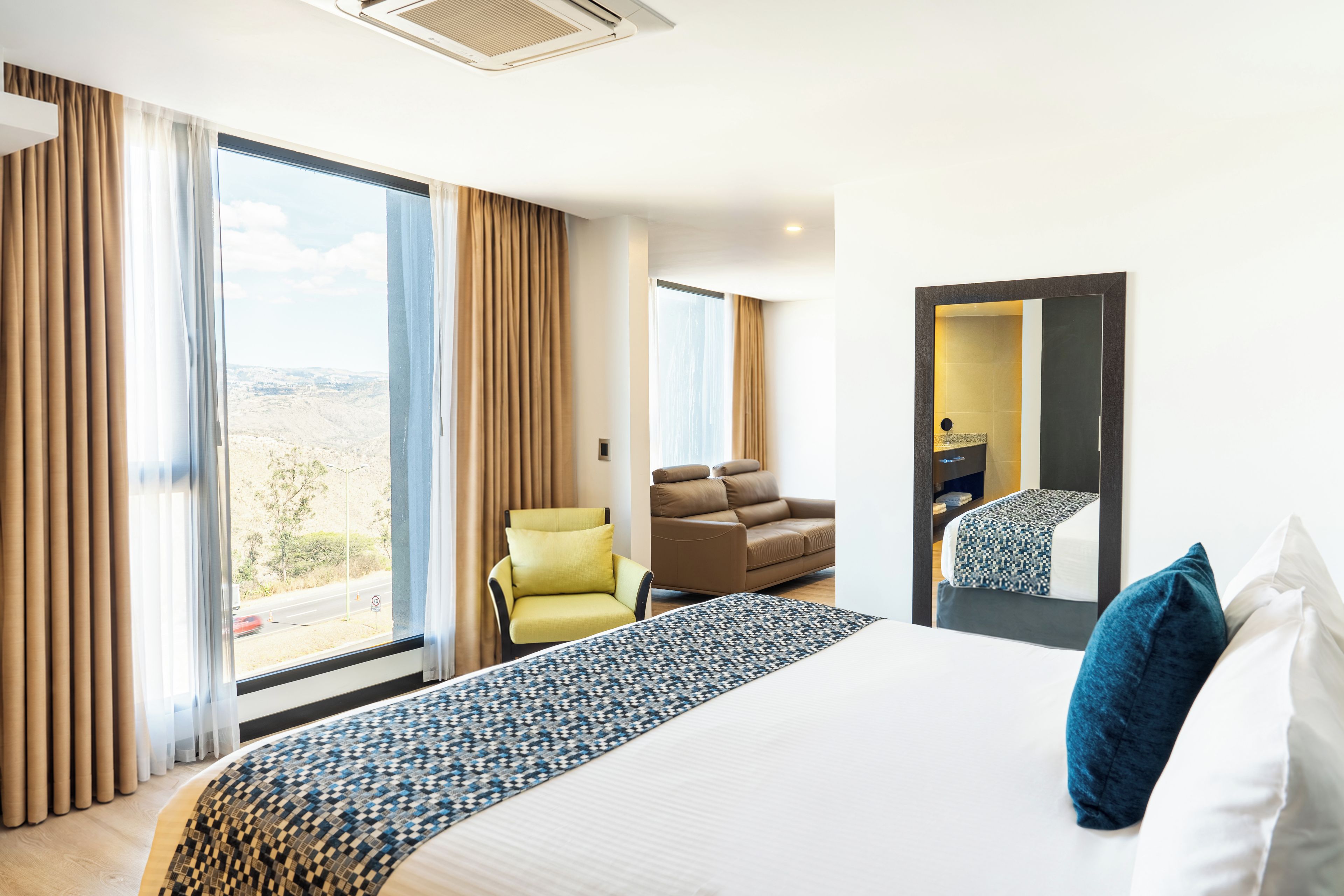 Una habitación de hotel con una cama grande, un sofá, una silla y vistas al exterior.