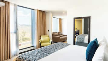 Una habitación de hotel con una cama grande, un sofá, una silla y vistas al exterior.