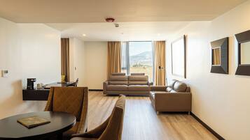 A modern hotel room with a dining area, a sofa, and a view of the outdoors.