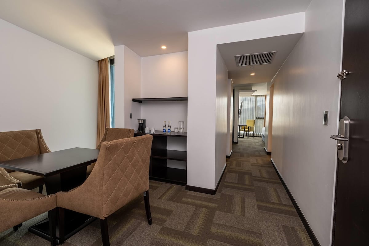 Habitación de hotel con comedor, kitchenette y pasillo que da a otras habitaciones.