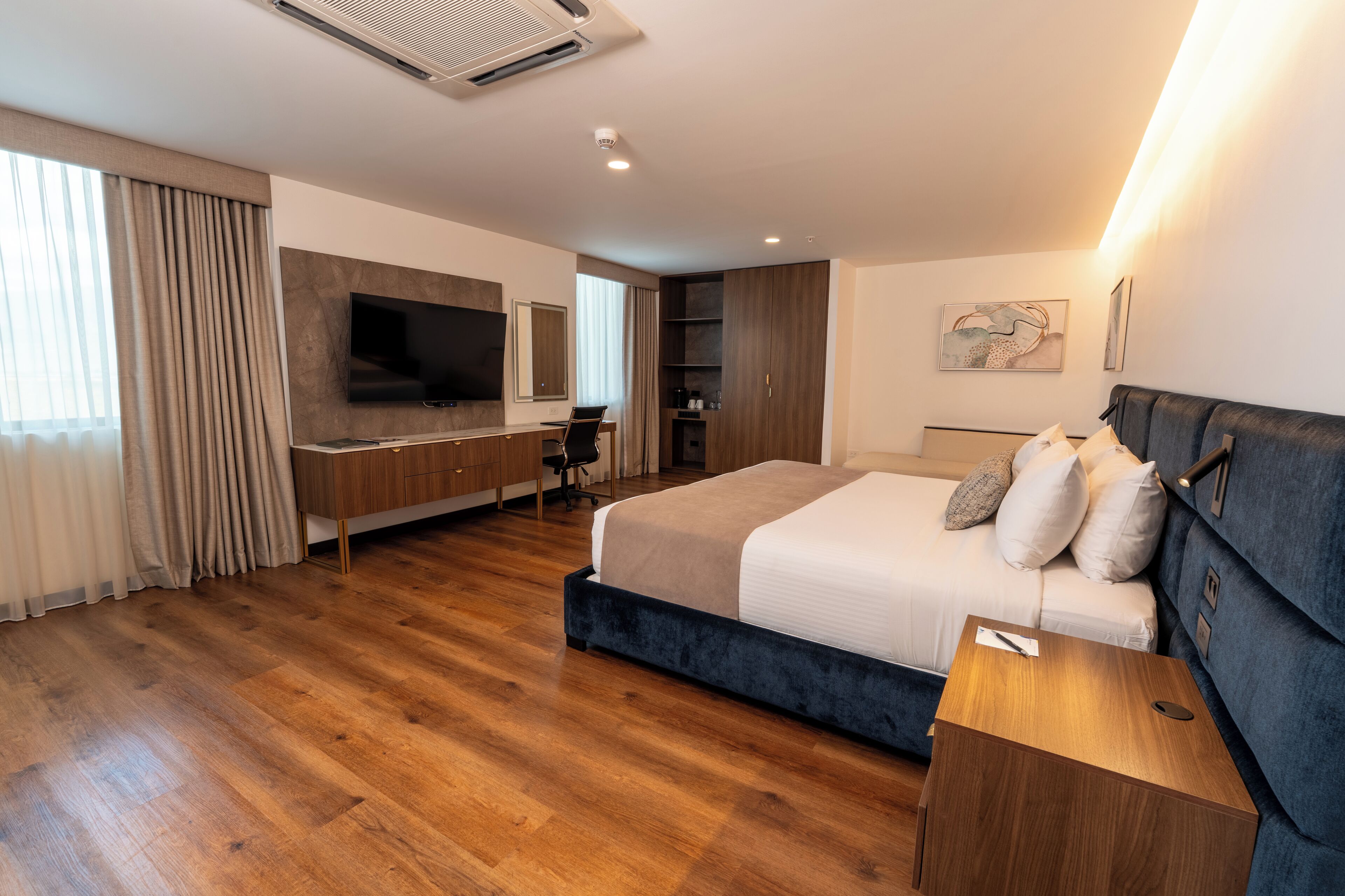 Una habitación de hotel moderna con una cama grande, un escritorio con silla, un televisor de pantalla plana y un armario.
