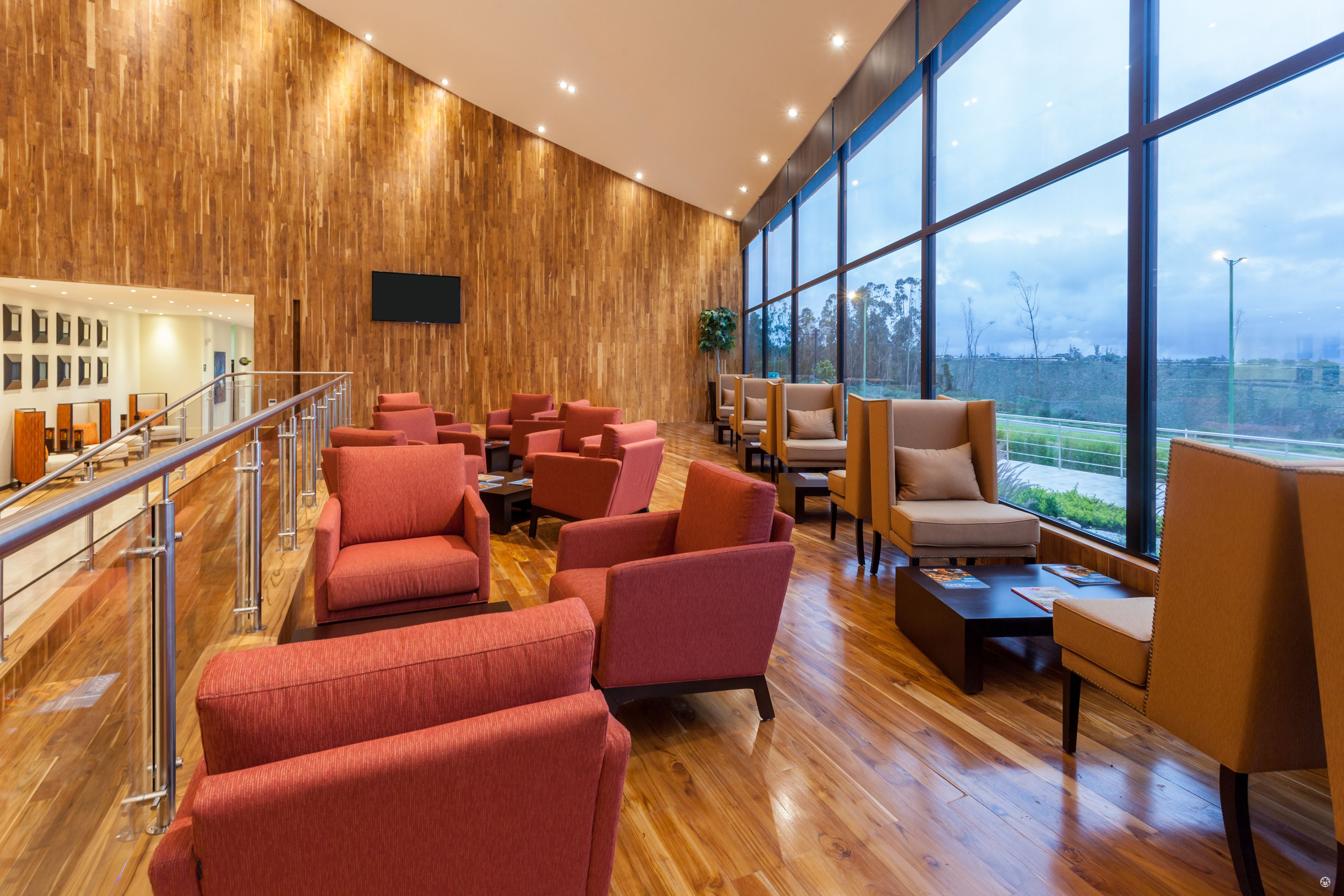 A spacious lobby with a wooden wall, large windows, and multiple seating areas.