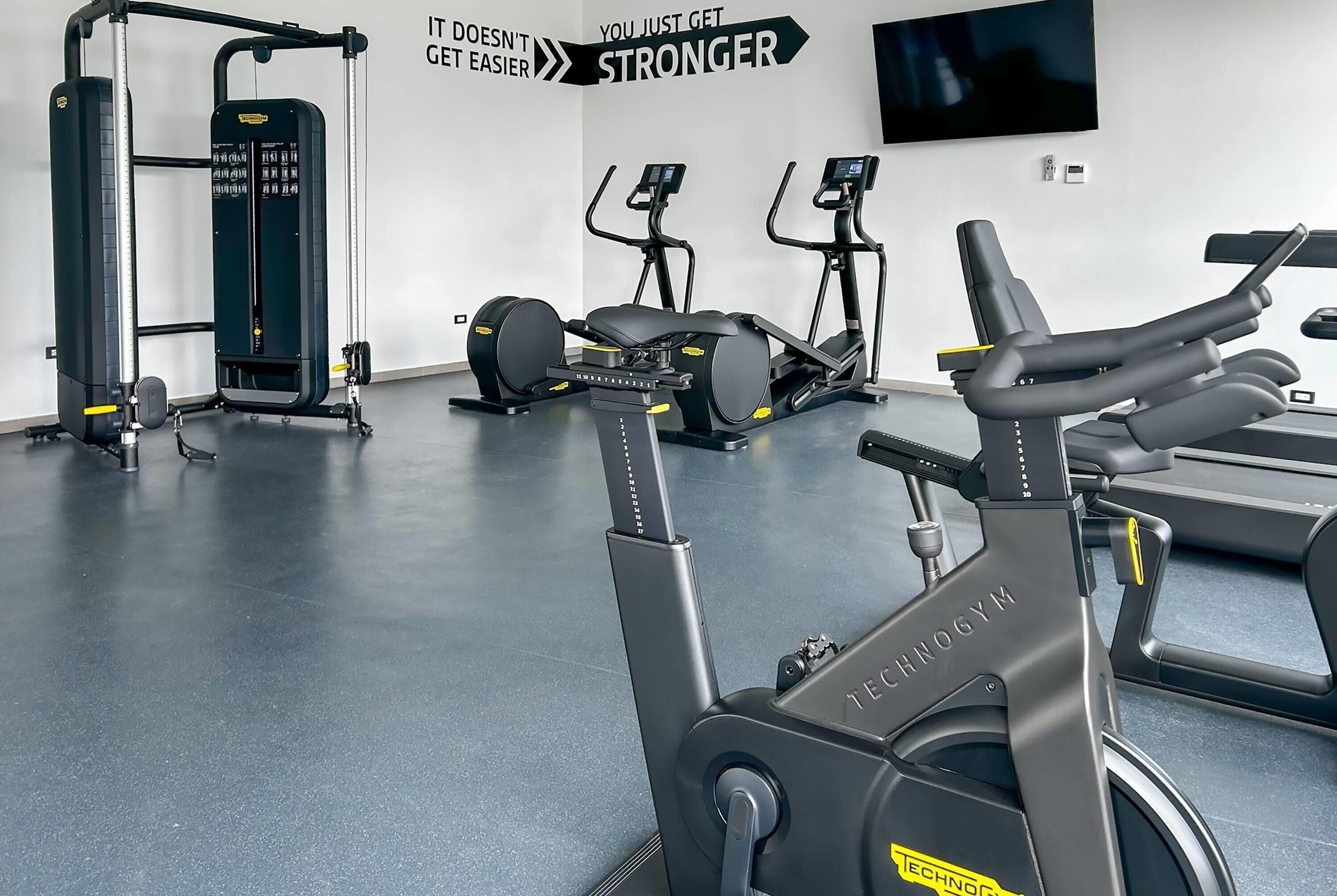 Un gimnasio con equipos de ejercicio variados, incluyendo cintas de correr, bicicletas estáticas y máquinas de pesas.