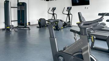 Un gimnasio con equipos de ejercicio variados, incluyendo cintas de correr, bicicletas estáticas y máquinas de pesas.