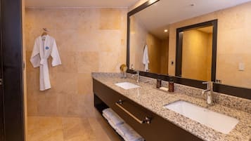 A modern bathroom with two sinks, a large mirror, and a robe hanging on the wall.