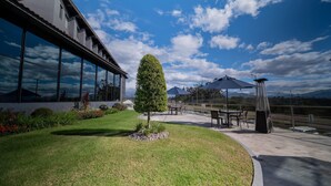 Un patio con mobiliario exterior, césped cuidado y vistas al cielo y a las montañas.