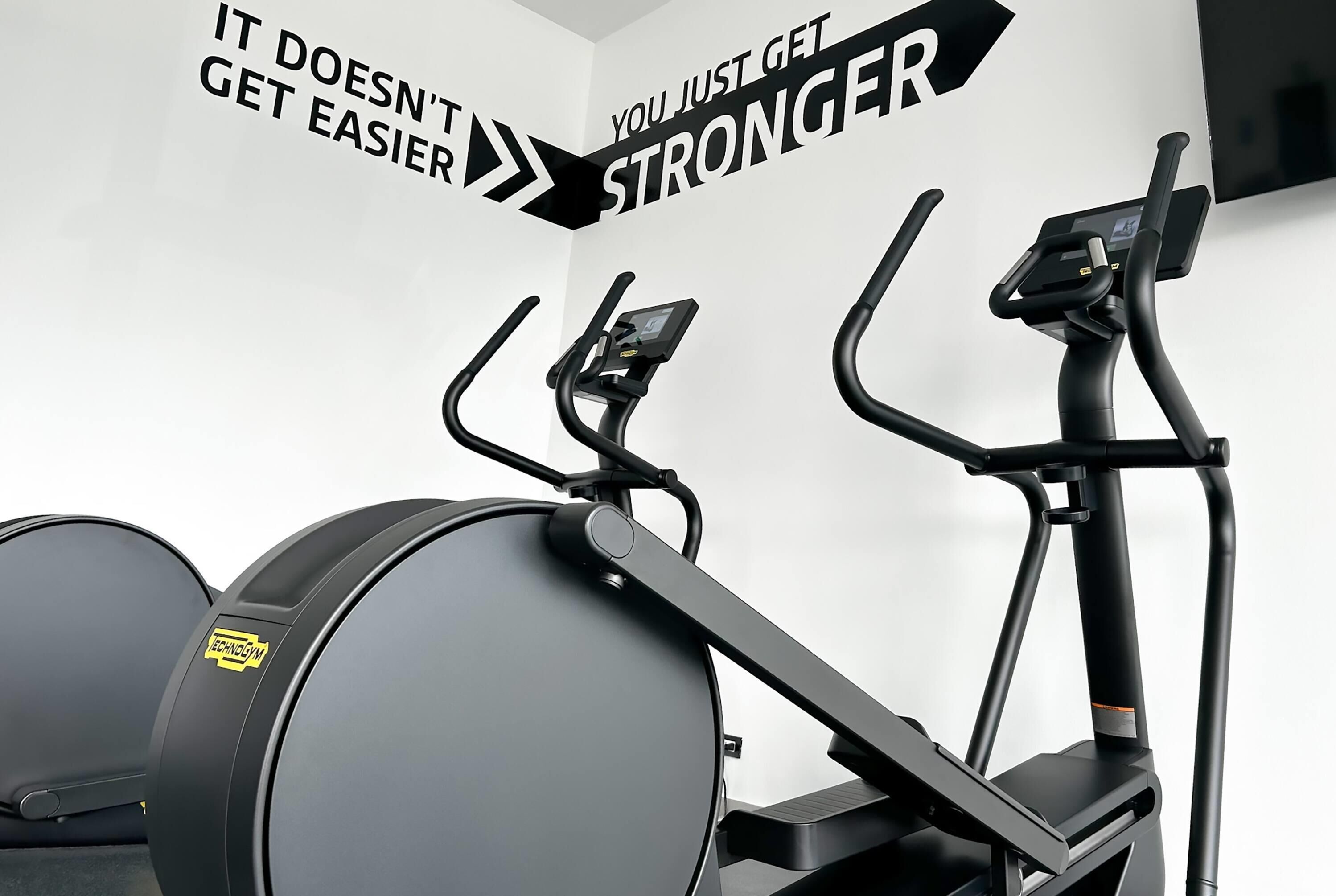 A gym with stationary bikes and a wall with motivational text.