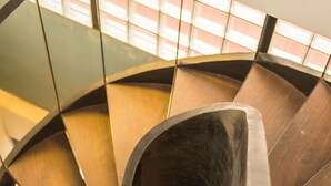 A spiral staircase with a metallic handrail and wooden steps. - The Purple Mangosteen (Siem Reap)