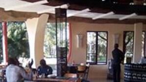 A spacious indoor area with tables and chairs arranged for dining. - Kaazmein Lodge (Livingstone)