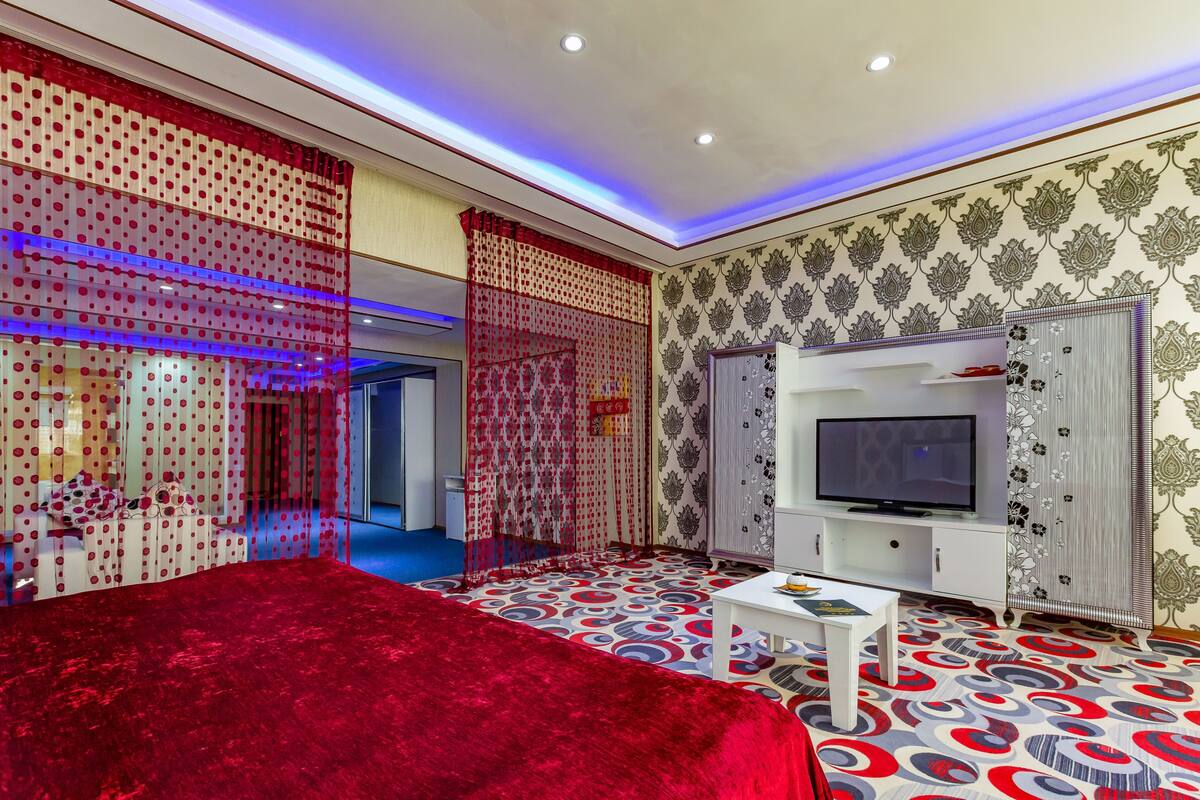A modern bedroom with a large bed, a TV, and a patterned floor.